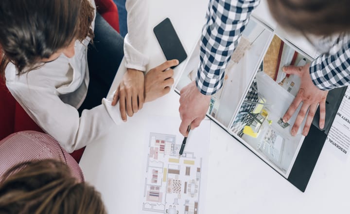 un consultor inmobiliario mostrando unos planos de vivienda